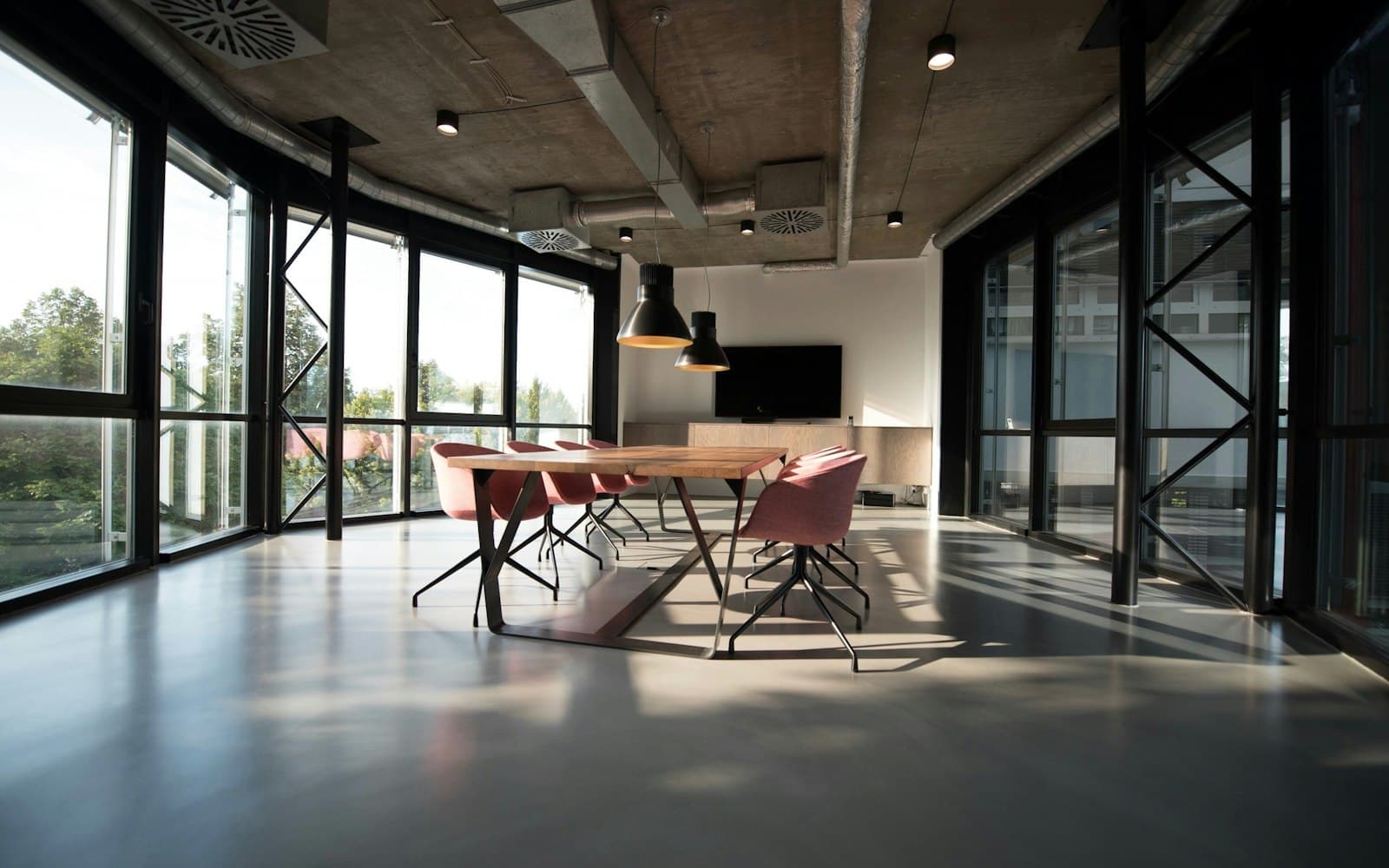 Loft studio with glazed walls, concrete ceiling and a long table